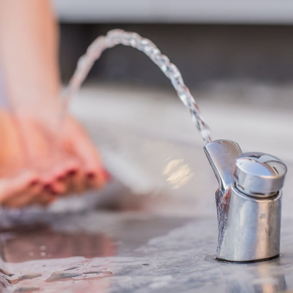 manos cogiendo agua del chorro de una fuente