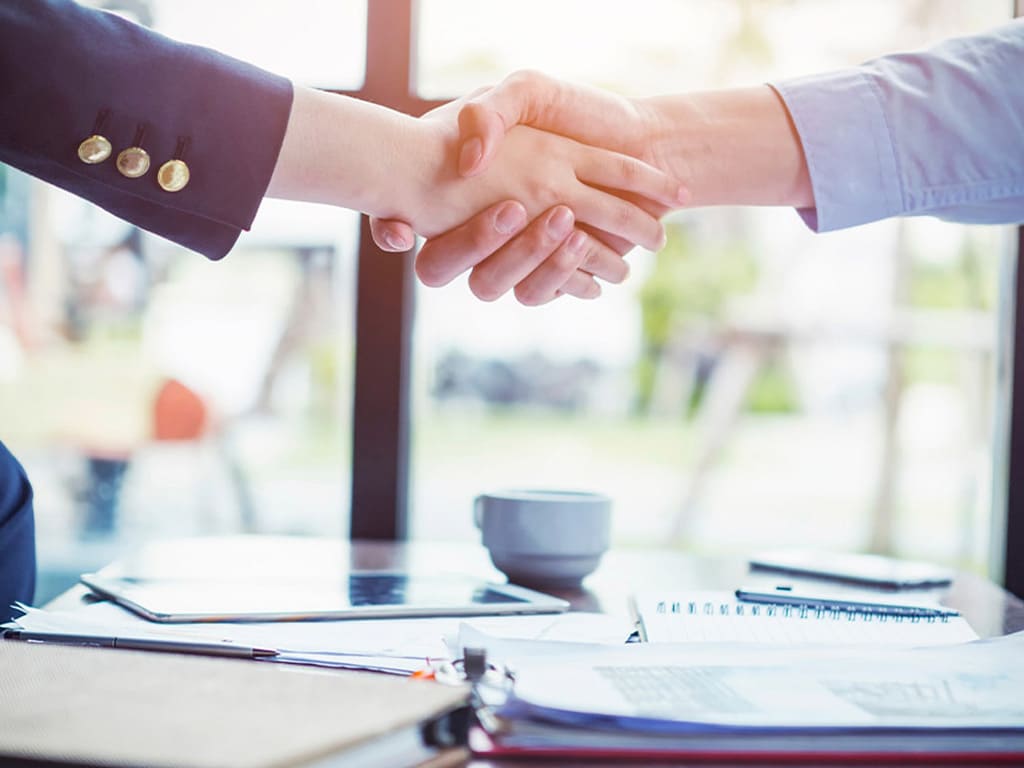 un hombre y una mujer dandose la mano para formalizar un contrato